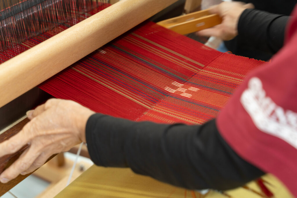 織り子さんが改良型織り機で実際に織っている手元の様子