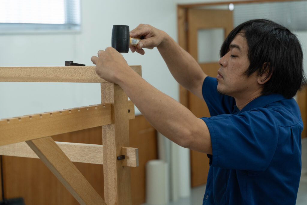 改良型織り機の組み立て中に各部の精度を確認する職人